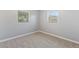 An empty bedroom featuring a carpeted floor, light gray walls, white trim, and two sunlit windows, creating an inviting space at 1085 Victor St, Aurora, CO 80011