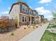 View of a cozy townhome with stone accents, a covered porch, and sidewalk access at 13754 Ash Cir, Thornton, CO 80602
