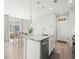 Open-concept kitchen features an island with sink, stainless steel dishwasher, and flows into the dining area and stairs at 13754 Ash Cir, Thornton, CO 80602