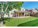 Lush backyard featuring a covered patio area, well-maintained lawn, and mature shade trees at 15122 Fillmore Way, Thornton, CO 80602