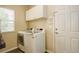 Laundry room with a window, white cabinets above a front-loading washer and dryer, and a white exterior door at 15122 Fillmore Way, Thornton, CO 80602