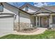 Home featuring stone accents, a two-car garage and manicured front yard at 15901 W 66Th Pl, Arvada, CO 80007