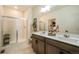 Well-lit bathroom featuring double sinks, wood cabinets, and glass shower at 2130 Indian Balsam Dr, Monument, CO 80132
