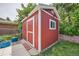 Exterior view of a red shed with white trim, a small window, and a door, set against a green lawn at 13472 E Dakota Ave, Aurora, CO 80012
