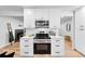 Modern kitchen features stainless steel appliances, white cabinets, light countertops, and light hardwood floors at 1810 S Kearney St, Denver, CO 80224