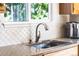 Close-up of a kitchen sink with stylish faucet, granite countertops, and white tile backsplash at 10482 Billings St, Commerce City, CO 80022