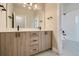 Modern bathroom featuring double vanity with wood cabinets, black hardware, and a tiled shower/tub at 2751 E 102Nd Pl, Thornton, CO 80229