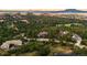 Scenic aerial view of a house surrounded by lush trees and hills against a backdrop of mountains and sunset at 6948 Fox Cir, Larkspur, CO 80118