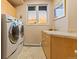 Functional laundry room features a sink with granite countertops and natural light from window overlooking a sunrise at 6948 Fox Cir, Larkspur, CO 80118