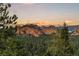 Striking mountain view amidst lush trees and a sunset backdrop, showcasing the natural beauty surrounding the property at 6948 Fox Cir, Larkspur, CO 80118