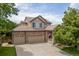 Charming two-story home featuring a brick facade, three-car garage, tile roof, and an inviting front porch with American flag at 13753 Monroe St, Thornton, CO 80602