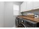 Laundry area with wooden counter, overhead storage cabinets, and front loading washer and dryer at 13753 Monroe St, Thornton, CO 80602