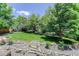Expansive backyard with lush green grass, mature trees, and lovely stone retaining walls and steps at 787 Eldorado Dr, Superior, CO 80027