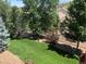 A well-maintained backyard features a lush green lawn, mature trees, white fencing, and garden at 3966 Aspen Hollow Ct, Castle Rock, CO 80104