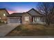Charming home featuring a stone facade, two-car garage, and well-maintained lawn at dusk at 3966 Aspen Hollow Ct, Castle Rock, CO 80104
