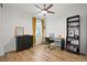 Well-lit bedroom featuring hardwood floors, a ceiling fan, and a desk with black shelves at 21440 E 61St Dr, Aurora, CO 80019