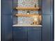 Elegant kitchen with custom navy cabinets, open shelving, and an eye-catching decorative backsplash at 21440 E 61St Dr, Aurora, CO 80019