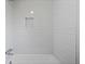 Bright bathtub and shower feature white subway tile, a shower niche, and sleek chrome fixtures at 10801 W 29Th Ave, Lakewood, CO 80215