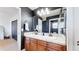 Bathroom featuring dual sinks with wood cabinets, white tile counters, and large mirror at 6051 E 160Th Pl, Brighton, CO 80602