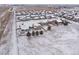 Winter aerial view of a residential neighborhood featuring snow-covered rooftops and open fields at 1523 Honeysuckle Ct, Brighton, CO 80601