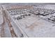 Winter aerial view of a residential neighborhood featuring snow-covered rooftops and open fields at 1523 Honeysuckle Ct, Brighton, CO 80601