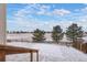 Backyard with a stone patio, trees, wood fence, and views of open space covered with snow at 1523 Honeysuckle Ct, Brighton, CO 80601