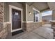 Inviting front porch with stone accents and a dark brown front door at 1523 Honeysuckle Ct, Brighton, CO 80601