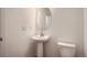 Clean half bathroom featuring a pedestal sink, round mirror, and modern fixtures at 13832 Honey Hush Trl, Parker, CO 80134