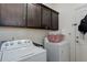 Laundry room with front-load washer and dryer, overhead storage, and access to exterior at 15222 E Batavia Pl, Aurora, CO 80011
