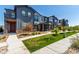 Inviting townhome featuring well-kept landscaping, stone accents, and covered porch entry at 157 Ambrose St, Erie, CO 80516
