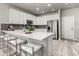 Modern kitchen features white cabinetry, stainless steel appliances, stylish backsplash, and a quartz countertop island with seating at 157 Ambrose St, Erie, CO 80516