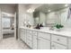 Bright main bathroom with double sinks, a large mirror, white cabinets, and a view into the main bedroom at 157 Ambrose St, Erie, CO 80516