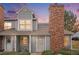 Charming townhome with a brick chimney and well-maintained landscaping at dusk at 8265 W 90Th Pl, Broomfield, CO 80021