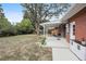 Brick house backyard featuring a covered patio, a large, mature tree, and partial fencing at 2251 Braun Dr, Golden, CO 80401