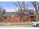Charming two-story brick home featuring mature trees and a well-maintained front yard on a sunny day at 841 Niagara St, Denver, CO 80220