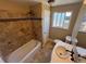 Bathroom featuring tile finishes, bathtub, vanity, and a window for natural lighting at 7021 Saulsbury St, Arvada, CO 80003