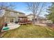 Spacious backyard with covered deck, lush lawn, mature trees, and stone patio at 23662 E Alabama Dr, Aurora, CO 80018