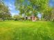 Expansive backyard featuring a well-maintained lawn, mature trees, and a charming brick home with a covered patio at 595 W Lake Ave, Littleton, CO 80120
