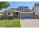 Home with a two-car garage, bay window, brick details, and a neatly kept lawn at 7054 S Flower Ct, Littleton, CO 80128