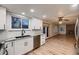 Well-lit kitchen with granite countertops, white cabinets, stainless steel dishwasher, and seamless flow into the living room at 7054 S Flower Ct, Littleton, CO 80128