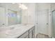 Bathroom with double sink vanity, neutral tile, and a glass-enclosed shower/tub at 4108 N Quatar Ct, Aurora, CO 80019