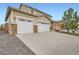 Home exterior featuring a three-car garage, concrete driveway, stone accents, and well-maintained landscaping at 56579 E 23Rd Pl, Strasburg, CO 80136