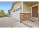 Close up of home exterior featuring a three-car garage with stone accents, and a covered front porch at 56579 E 23Rd Pl, Strasburg, CO 80136