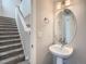 This powder room features stairs, a pedestal sink with modern faucet, and a stylish, round mirror at 4773 Kittredge St, Denver, CO 80239