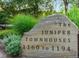Stone sign displaying 'The Juniper Townhouses' address, surrounded by green shrubs and manicured landscape at 1172 Juniper Ave, Boulder, CO 80304