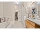 Bright bathroom with a soaking tub, walk-in closet, and vanity with wood cabinets and neutral countertop at 6001 S Yosemite St # F207, Greenwood Village, CO 80111