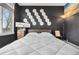 This primary bedroom features stylish accent wall, decorative bedside table, and comfortable white quilted bedding at 6001 S Yosemite St # F207, Greenwood Village, CO 80111