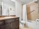 Bathroom with a tile shower, grab bar, shower curtain, toilet, sink, and dark wood cabinets at 7323 Lowell Blvd, Westminster, CO 80030