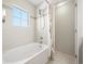 Clean and crisp bathroom with a shower-tub combo with white tile, a window, and shower curtain at 7323 Lowell Blvd, Westminster, CO 80030