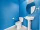 Compact powder room featuring a pedestal sink, toilet, tile floors, and bright blue walls at 7323 Lowell Blvd, Westminster, CO 80030